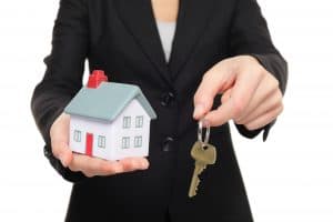 Man holding house keys and model house